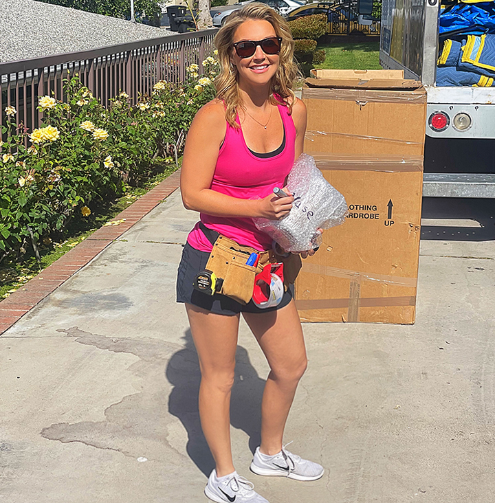 young couple smiling while carrying boxes into their new home