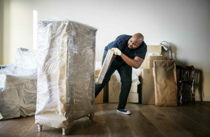 Moving company employee wrapping furniture